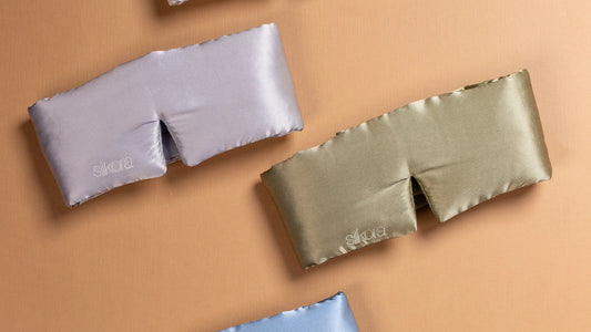 Zijden slaapmaskers van Silkora in zilvergrijs en olijfgroen op een zandkleurige achtergrond