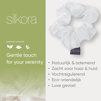 Promotieafbeelding van een grote Silkora premium scrunchie in wit, met tekst over natuurlijke, ademende, vochtregulerende en eco-vriendelijke eigenschappen.